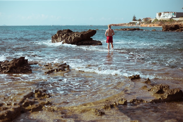 The guy stands on the rocks by the sea