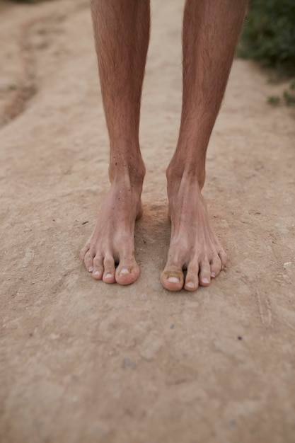 The guy stands on the sand barefoot feet close up