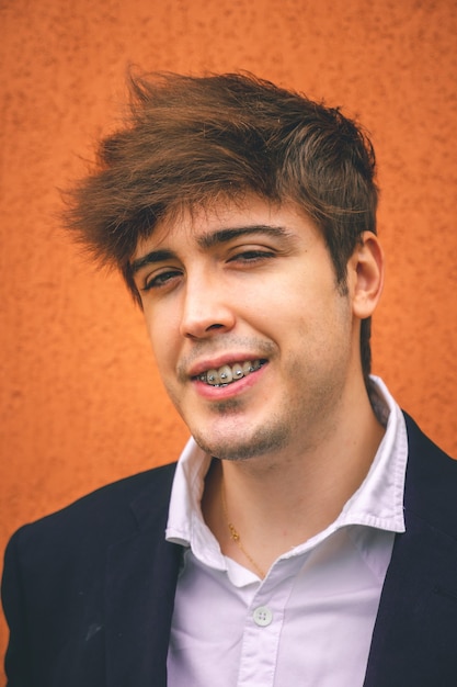 Guy in suit smiling on an orange wall