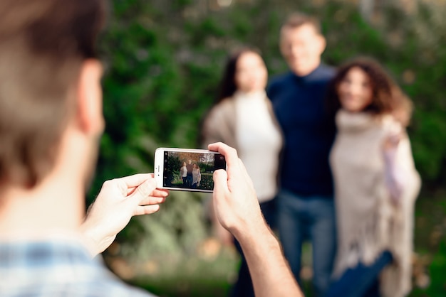 A guy takes pictures of friends on a smartphone.