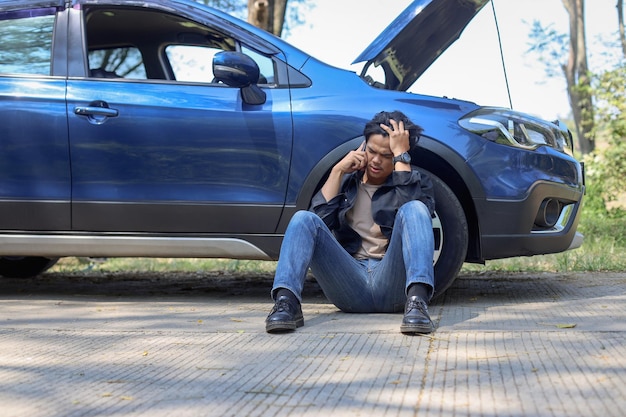 guy talking on the phone to ask for a mechanic to come fix his brokendown car in the highway