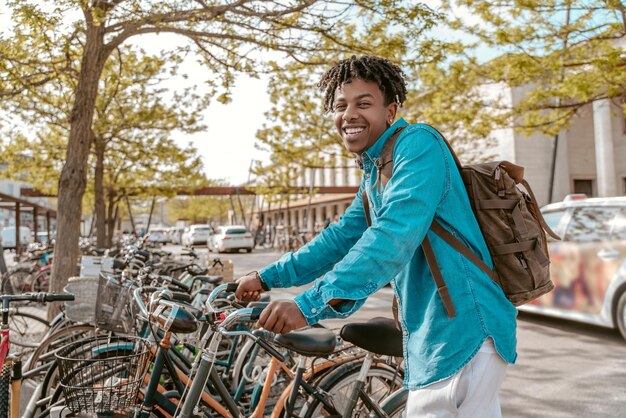 Guy touching bicycle smiling at camera on street