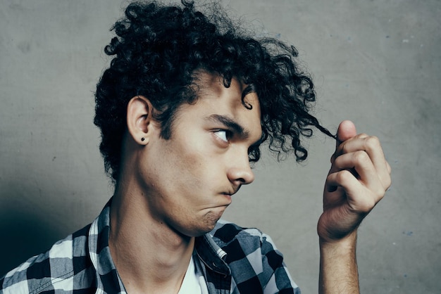 Photo guy in a tshirt and in a plaid shirt examines his hair on a gray background cropped view closeup high quality photo