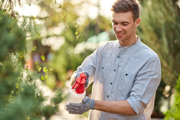 Guy tuinman spuit op een zonnige dag water op planten in de prachtige kwekerij. werk in de tuinman.