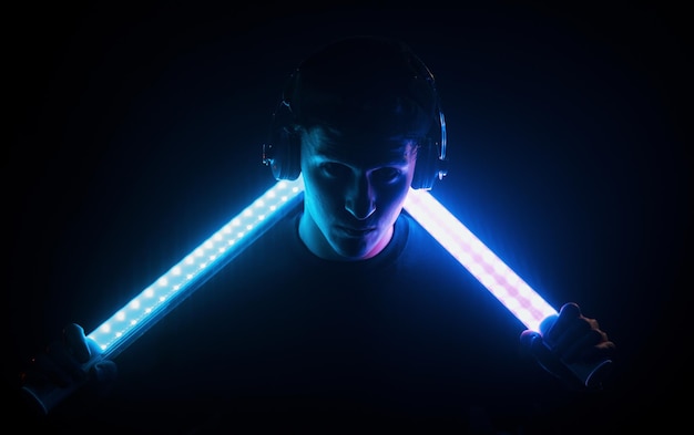 Photo guy uses headphones neon lighting young european man is in the dark studio