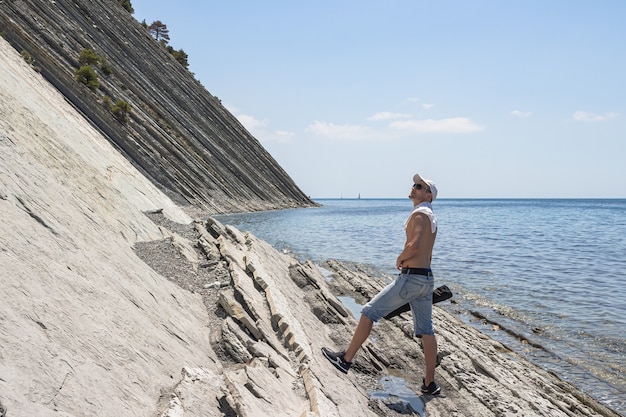 写真 石の野生のビーチを歩いている男が立ち止まって見上げた。ゲレンジークのリゾート都市。ロシア、黒海沿岸