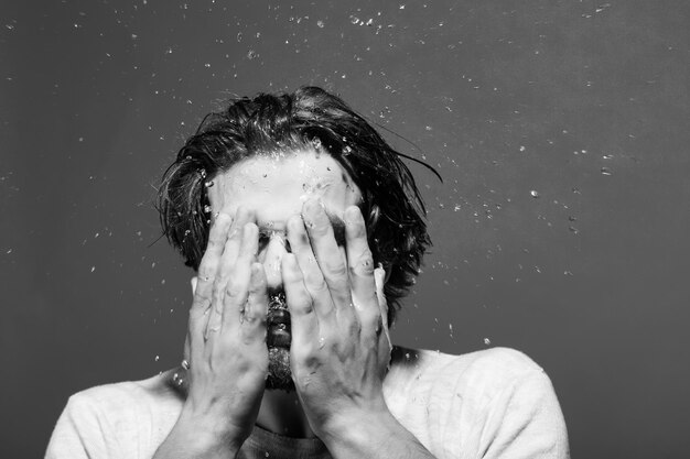 Photo guy washing face with water drops in morning