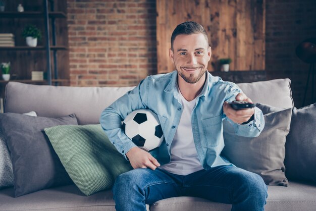 guy watch football match hold ball remote controller