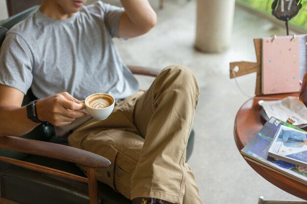 Photo guy wearing cargo pants and drinking a coffee in coffee shop