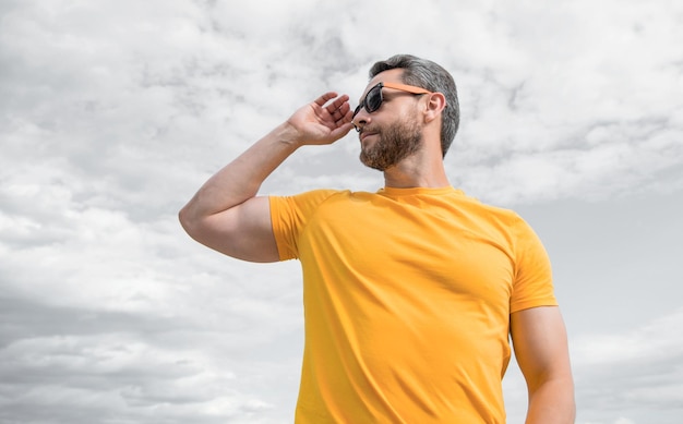 guy wearing yellow shirt and sunglasses outdoor on sky background