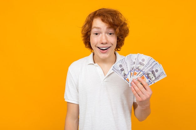 Guy in a white shirt holds money won on a yellow background with copy space.