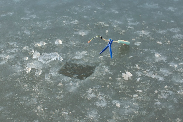 The guy on the winter fishing at the hole catches a small\
fishing pole