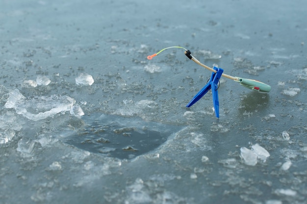 The guy on the winter fishing at the hole catches a small fishing pole