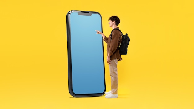 Guy With Backpack Using Giant Phone With Empty Screen Studio