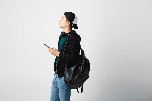 парень с черным рюкзаком пользуется мобильным телефоном