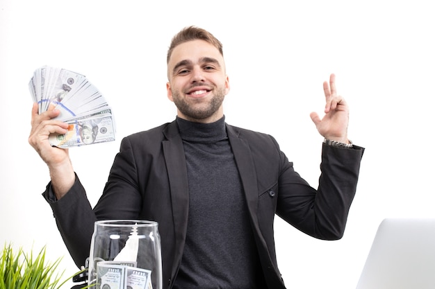 A guy with business clothes shows the earnings while sitting at the workplace