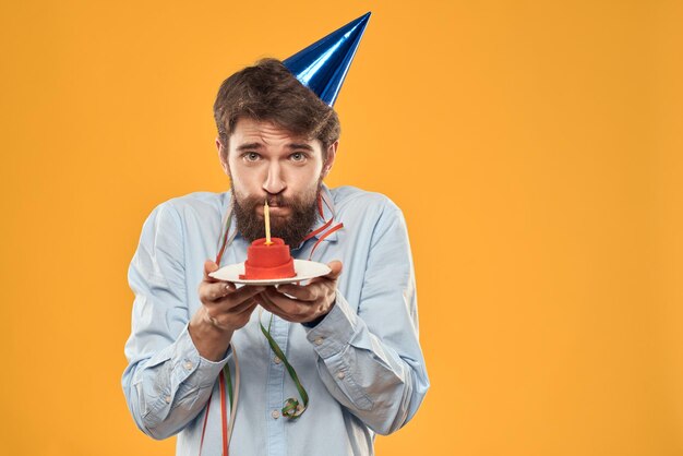 Guy with a cake in a plate on a yellow background holidays candle cropped view person