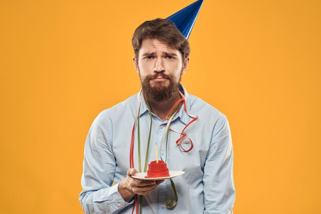 Guy with a cake in a plate on a yellow background holidays candle cropped view person