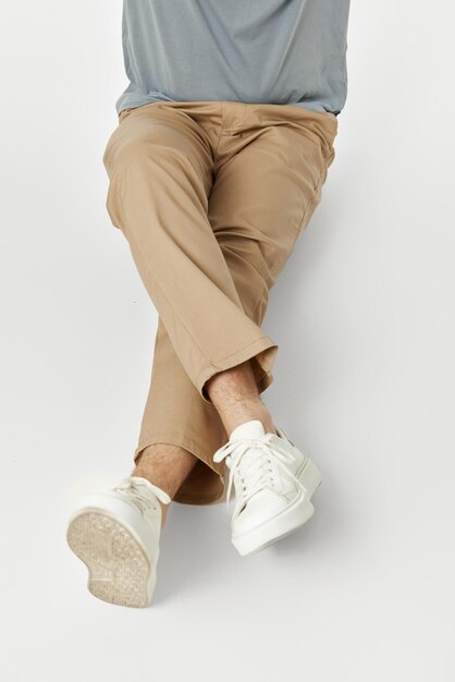 写真 白いスニーカーとベージュのズボンを履いて床に座っている横足の男
