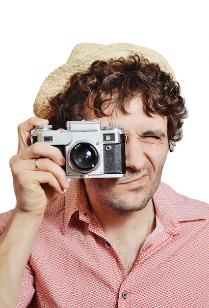 Guy with curly hair in a hat with a vintage camera takes pictures