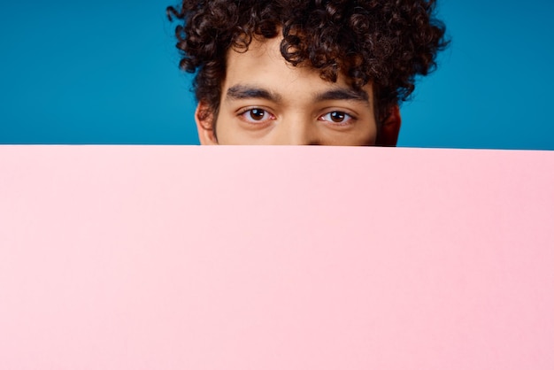 Guy with curly hair holding pink Poster mockup Coffee Space High quality photo