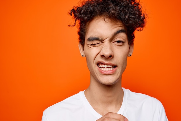 Guy with curly hair in a white tshirt emotion grimace High quality photo