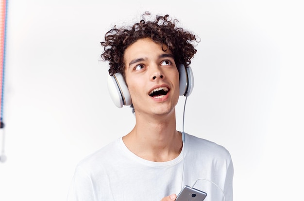 Guy with curly hair in a white tshirt listens to music technology