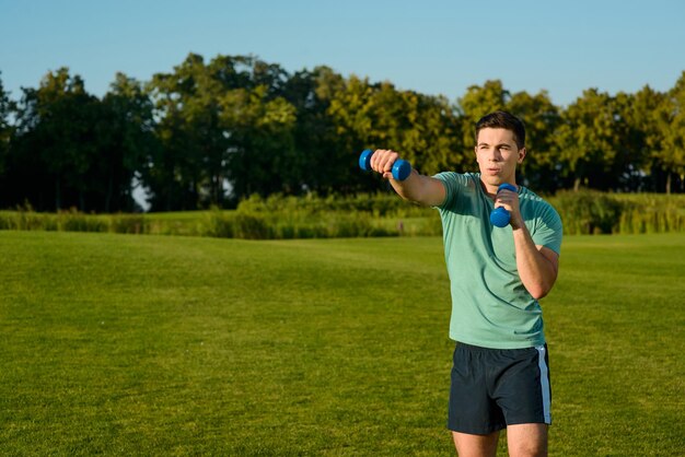 Guy with dumbbells on a lawn