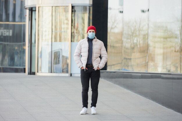 A guy with a face mask on the face because of the pandemic walking on the street