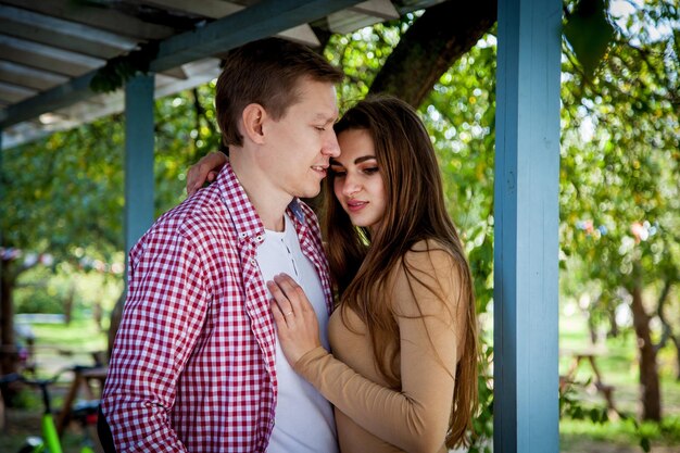 The guy with a girl hugs near a wooden house