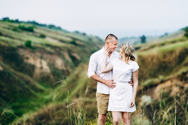 A guy with a girl in light clothes on the background of a green canyon of erosion of the earth