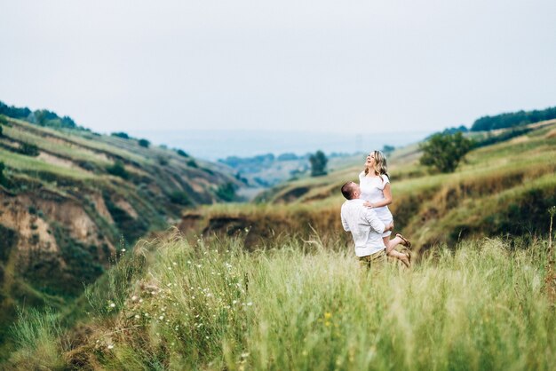 A guy with a girl in light clothes on the background of a green canyon of erosion of the earth