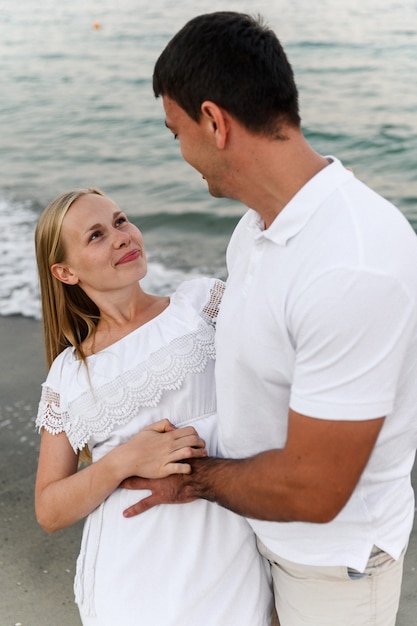 夏服を着た女の子と一緒に海を歩いている男。海の近くの日のロマンチックな夕日で夫と妻。