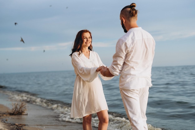 Un ragazzo con una ragazza in abiti bianchi in riva al mare