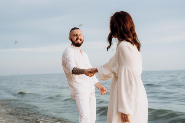 Un ragazzo con una ragazza in abiti bianchi in riva al mare