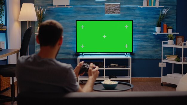 Парень с современным телевизором с зеленым экраном в гостиной