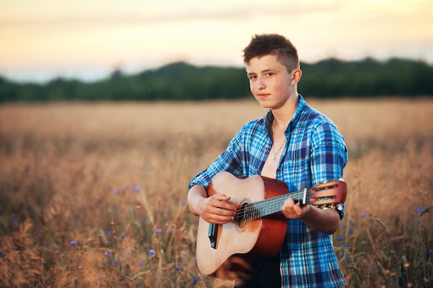 Guy with a guitar playing songs at sunset nature