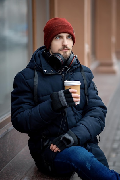 ヘッドフォンとコーヒーを持った男