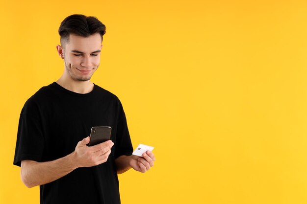 Photo guy with phone and credit card on yellow background