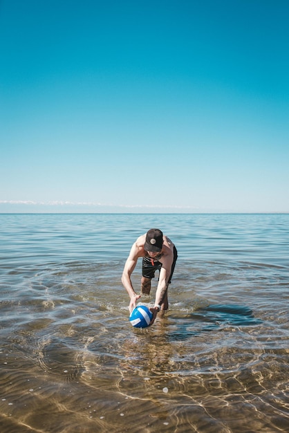 guy with a volleyball ball at sea on a summer day