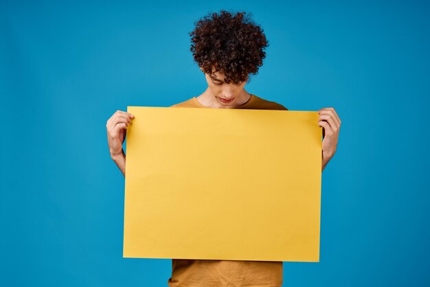 Guy with yellow poster in hands Copy Space advertising blue background High quality photo