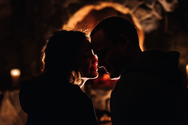 Guy and woman are sitting in a wooden house against of a burning fireplace