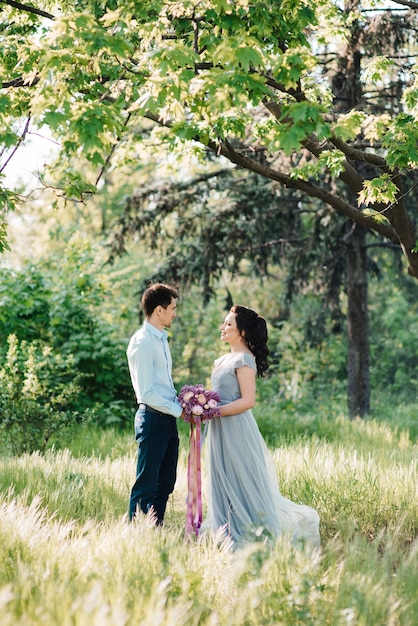 A guy and a woman walk in the spring garden of lilacs before the wedding ceremony