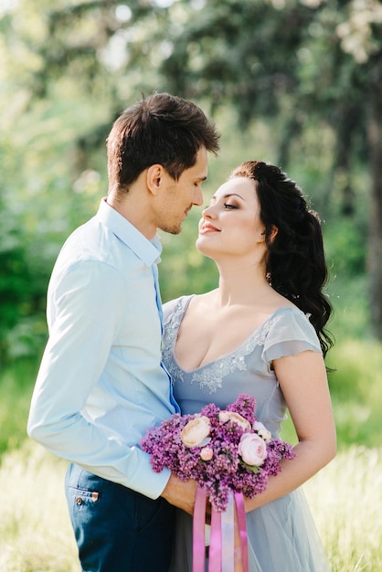 A guy and a woman walk in the spring garden of lilacs before the wedding ceremony