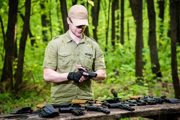 森にいる男は射撃スポーツのために彼の武器をテストします