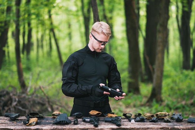 guy in the woods tests his weapons for shooting sports