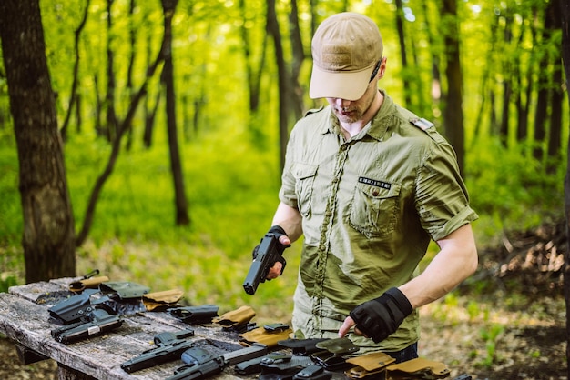 森にいる男は射撃スポーツのために彼の武器をテストします