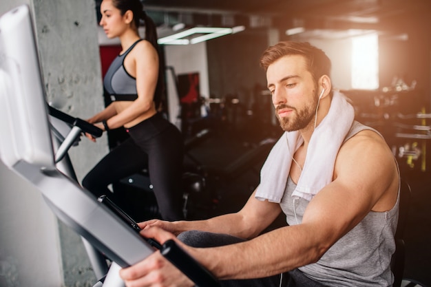 guy working on the exercise bike and his girlfriend doing the same thing further down