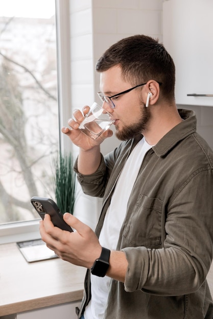 男は遠くで働いて水を飲むビデオ通話のコンセプト自宅での健康的なライフスタイル