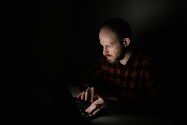 The guy works on a laptop or looks at something in the dark